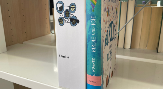 Das Buch "Birdie und ich" steht im Regal neben dem Kategorieaufstellr "Familie".