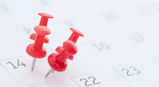 Kalender im Hintergrund. vier rote Pins sind in den 14. Tag des Monats gepint.